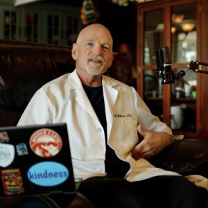 Man in lab coat sitting with laptop.